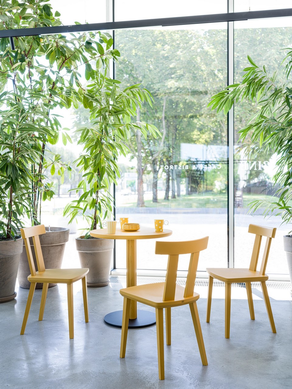 Espace de restauration lumineux avec tables ONE jaunes et base acier plate pour un gain de place.