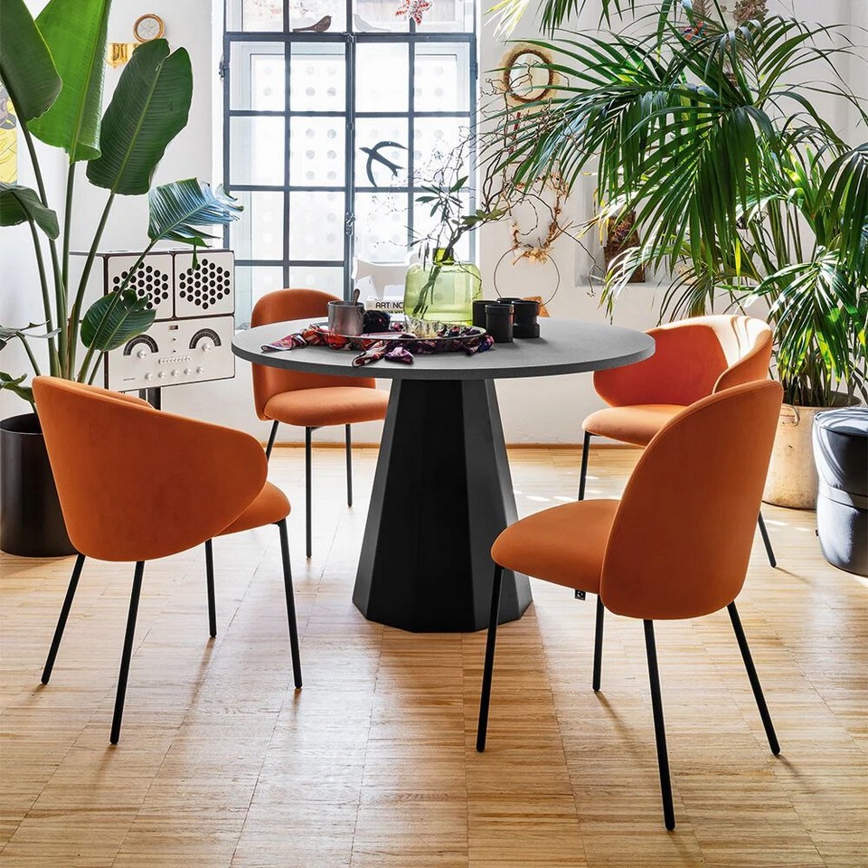 Ensemble de chaises et de fauteuils de réunion TUKA orange disposées autour d'une table ronde pour un espace collaboratif dynamique et moderne.