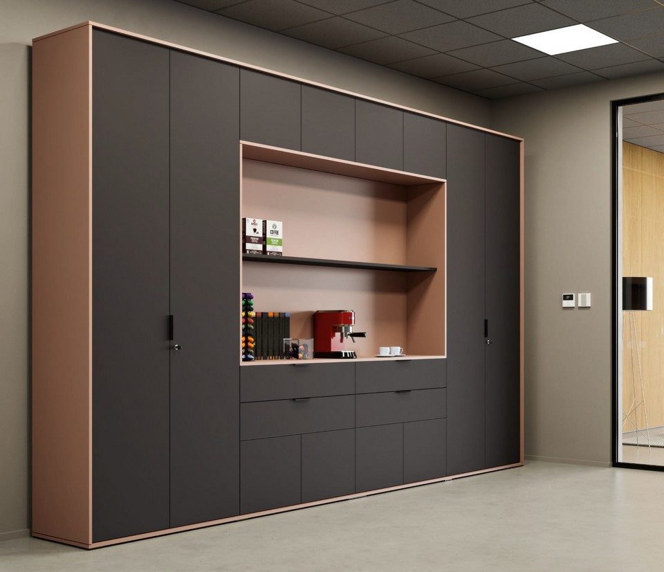 Vue en perspective de l'armoire de bureau personnalisable GALAXY configurée en tisanerie haut de gamme. Le meuble de rangement combine des façades laquées gris anthracite mat et un cadre de finition cuivre rose. La grande niche centrale ouverte est aménagée en espace café élégant avec une machine expresso et des étagères de rangement pour l'agencement d'un open space ou d'un bureau de direction.
