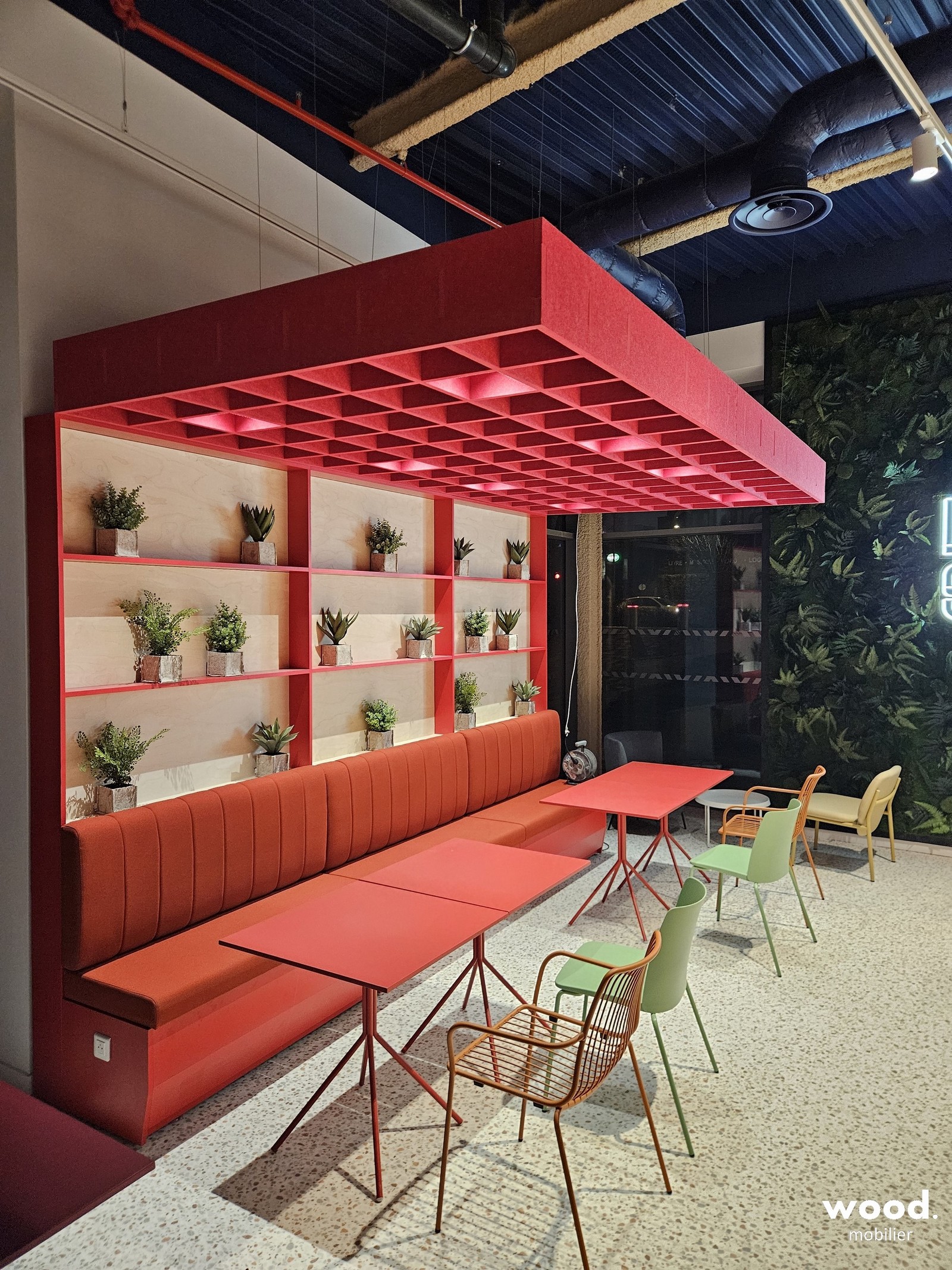 Structure acoustique rouge en grille de PET recyclé pour le traitement sonore d'un restaurant d'entreprise sous haut plafond.