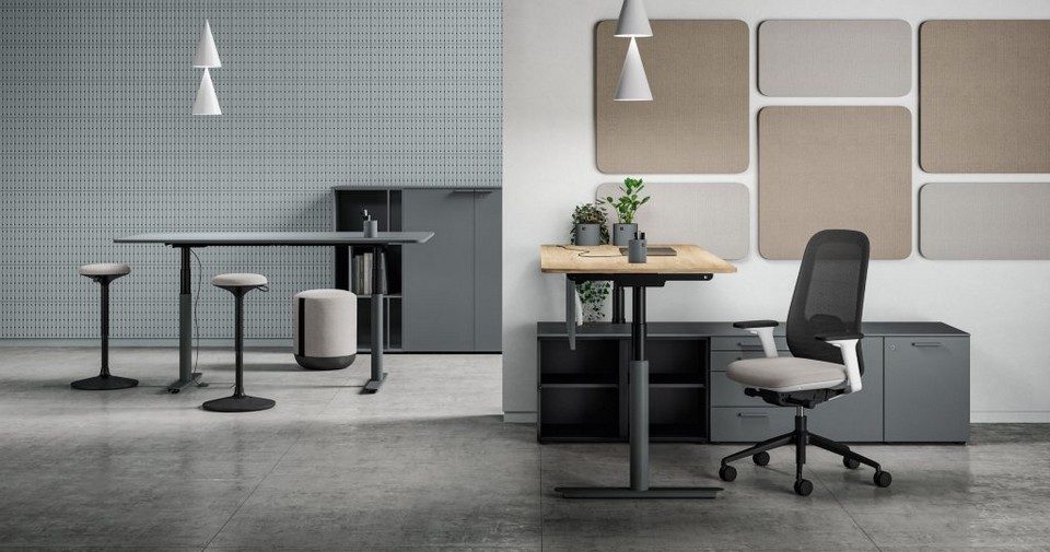Bureaux assis-debout réglables en hauteur NUVOLA de Bralco avec plateaux bois et anthracite, chaises ergonomiques et cloisons acoustiques murales dans un open space moderne au style industriel.