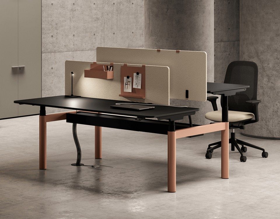 Bureau assis-debout double NUVOLA de Bralco configuré en bureau bench pour open space. Postes de travail réglables en hauteur avec piétement métallique couleur terracotta, plateaux noirs et cloisonnette de séparation acoustique beige.