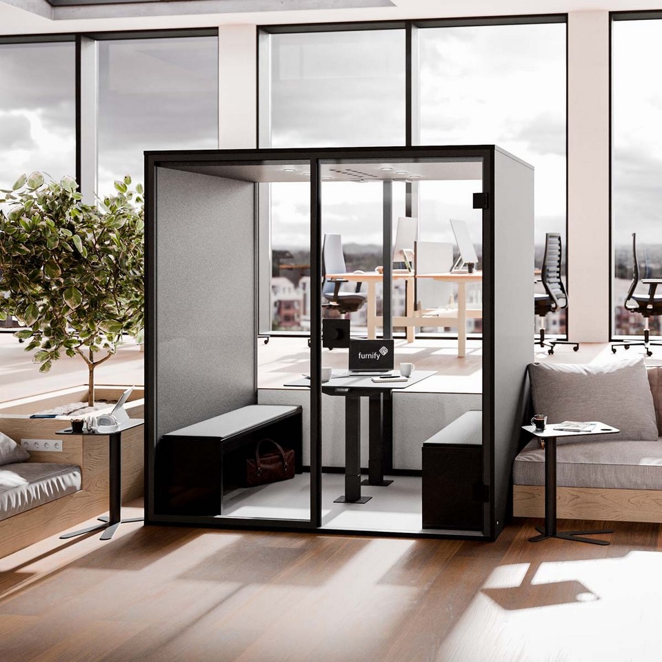Grande cabine acoustique BERLIN MEET pour 4 personnes avec assises lounge, intégrée dans un bureau ensoleillé (met en avant le confort et le design).