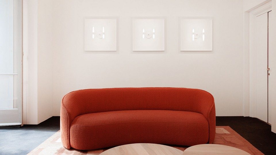 Canapé d'attente organique SIBILLINO en tissu bouclé rouge, agencé sur un tapis dans un espace lounge ou bureau de direction au design minimaliste.