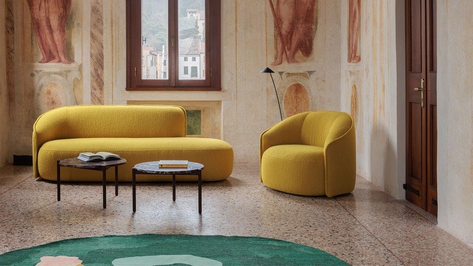 Canapé lounge et fauteuil d'attente SIBILLINO en tissu bouclé jaune moutarde, disposés dans un salon de réception classique avec tables basses en marbre.