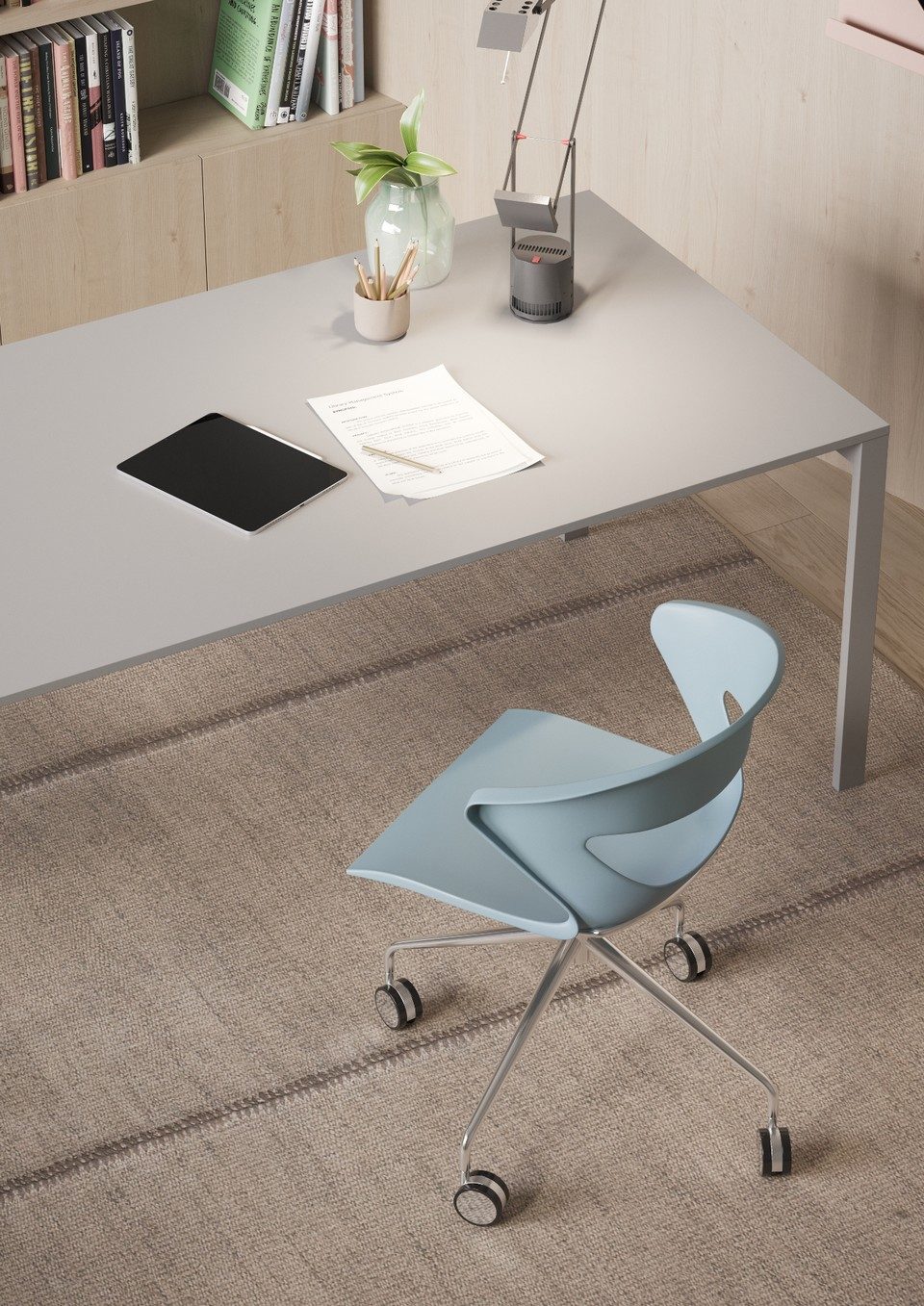 Chaise de bureau pivotante KICCA bleu nuage avec piètement chrome à quatre branches sur roulettes, installée devant un bureau minimaliste gris.
