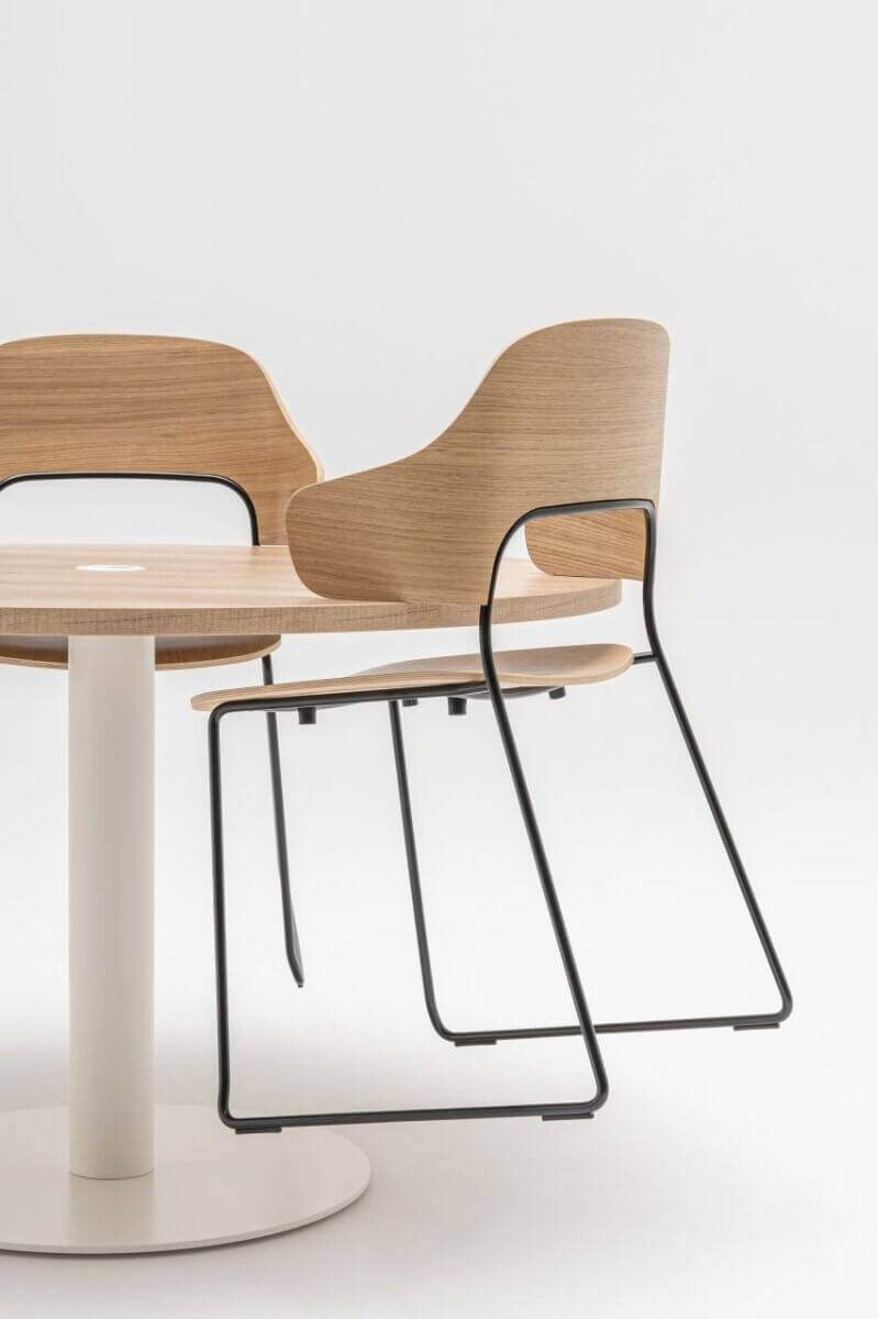 La chaise de restaurant design FEEL possède des accoudoirs qui permettent de la suspendre à la table.