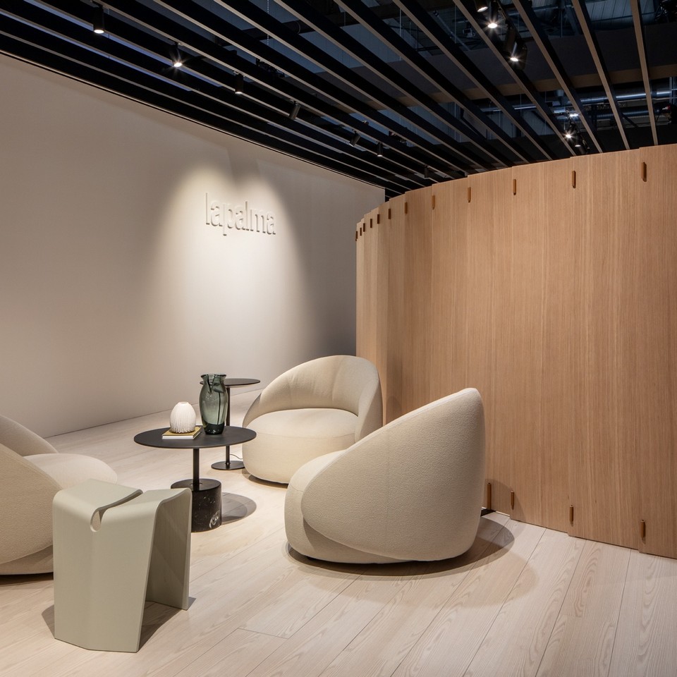 Aménagement d'un espace lounge chaleureux délimité par le claustra bois courbe WOD, créant une zone d'attente intime et design.