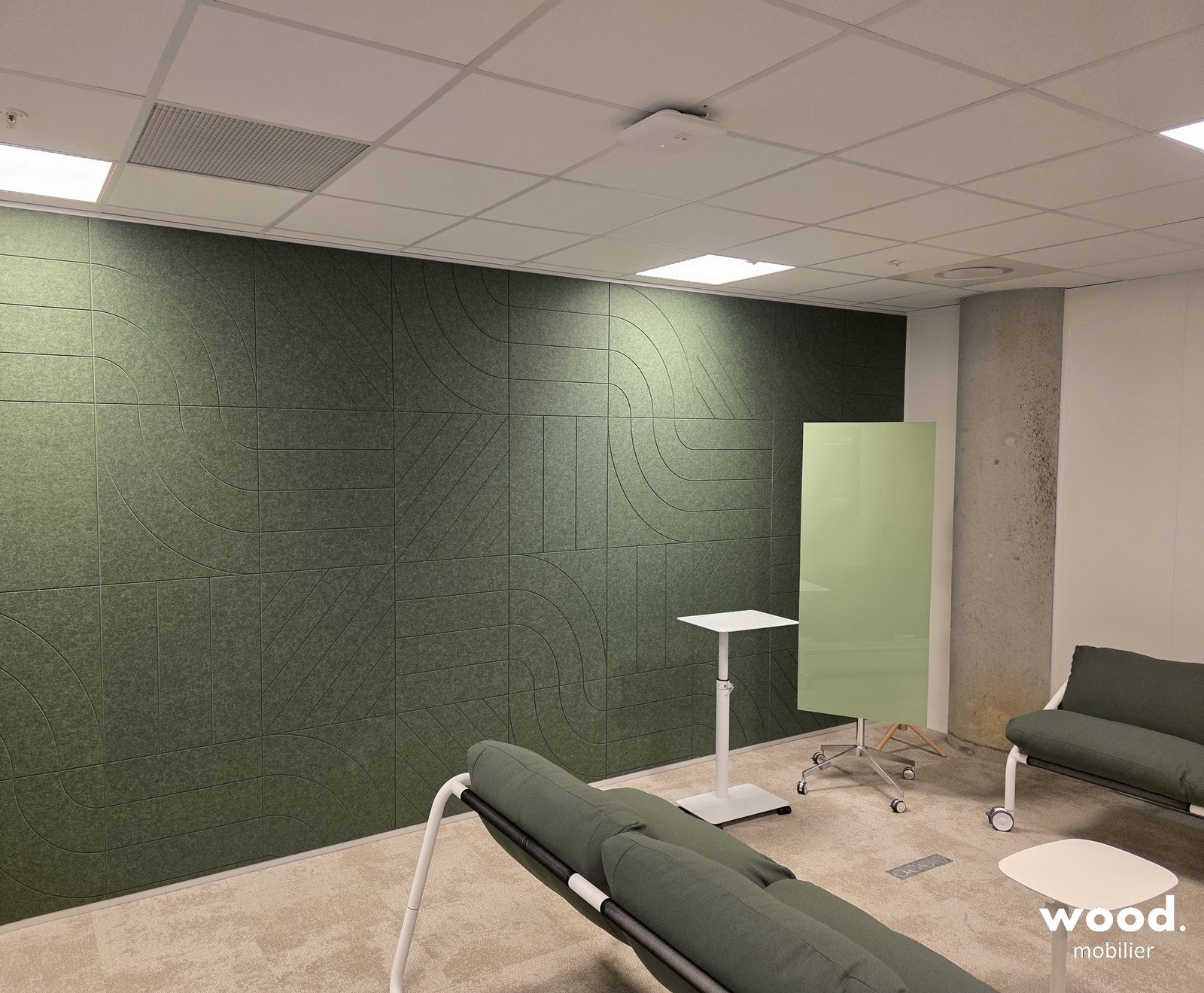 Aménagement d'un espace de détente avec mur acoustique vert absorbant et mobilier de bureau ergonomique à Lille.