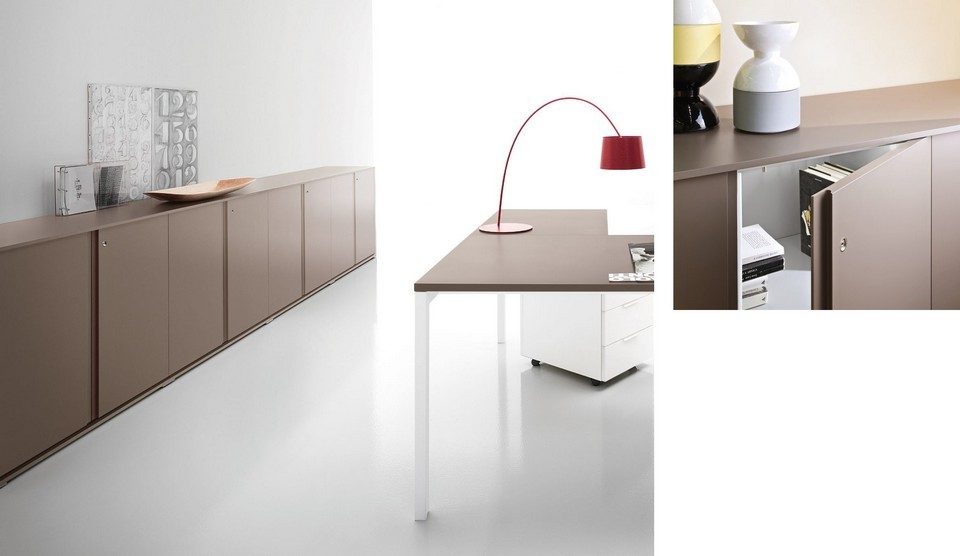 Vue d'une crédence de bureau basse de la gamme GALAXY en finition laquée taupe mat avec portes battantes push-pull. Le visuel principal présente le meuble bas filant dans un open space épuré à côté d'un bureau, tandis que le plan serré montre l'ouverture d'une porte sur des étagères de rangement intérieures accueillant des livres et des dossiers.