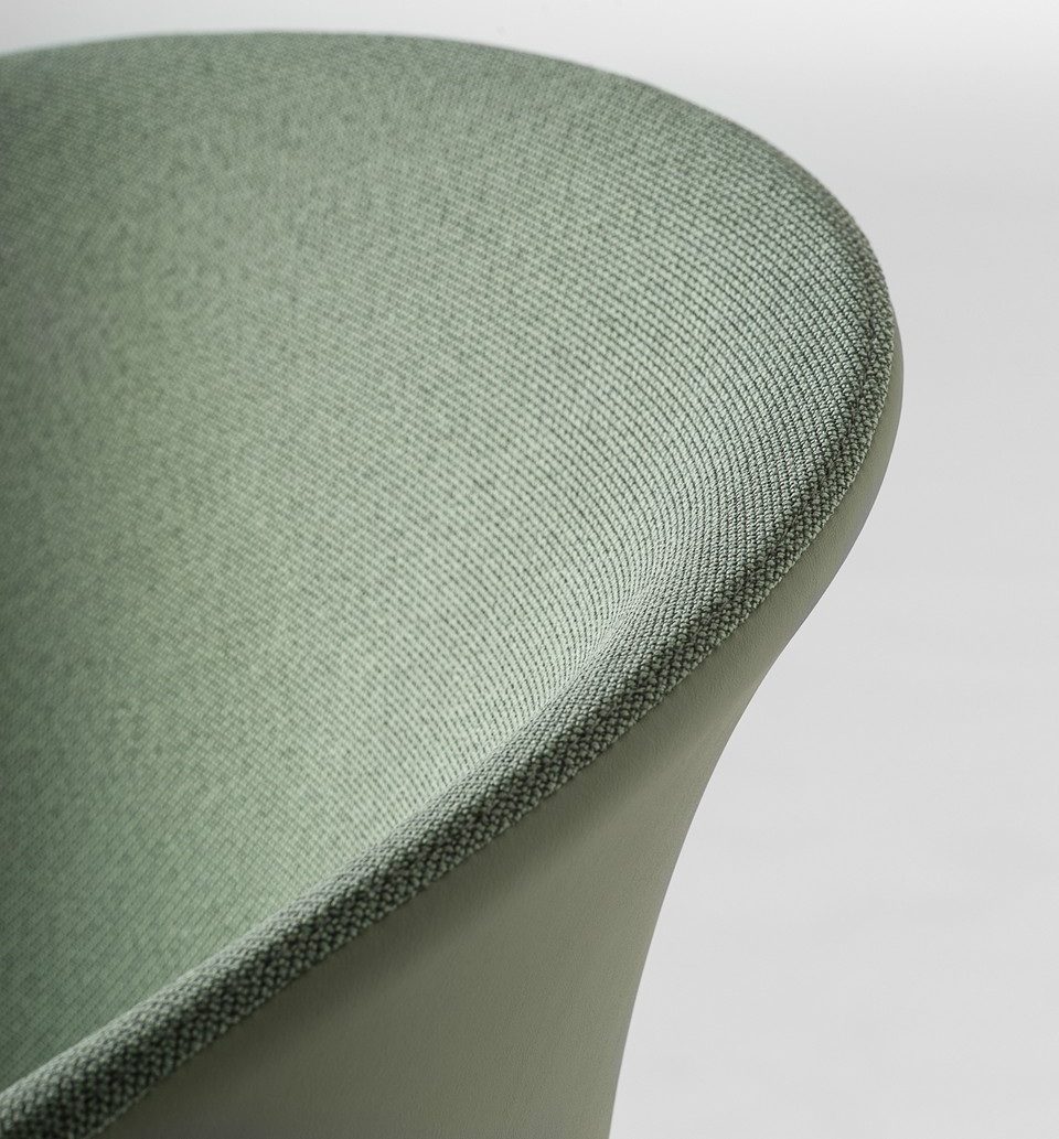 Gros plan sur la coque tapissée d'une chaise KICCA PLUS vert olive, illustrant la possibilité d'une finition bi-matière (tissu et cuir) et la qualité des coutures.