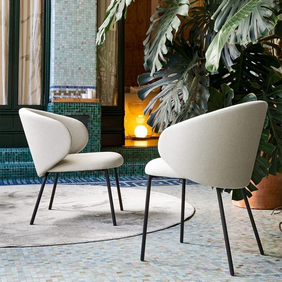 Deux chaises, une de réunion, et l'autre pour les espaces lounge, de la collection TUKA avec revêtement en tissu blanc et pieds noirs, offrant une esthétique épurée pour un bureau de direction haut de gamme.