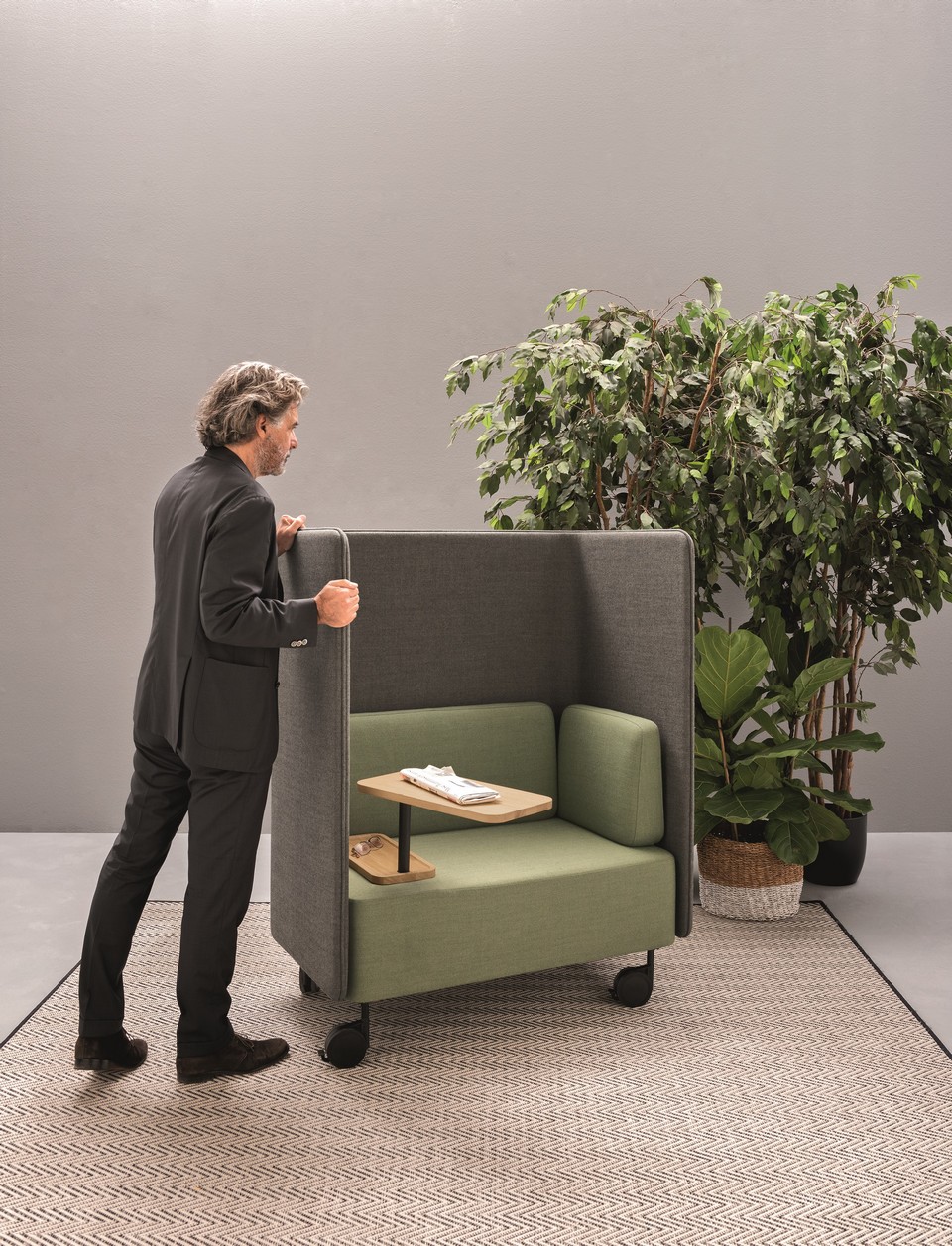 Utilisateur déplaçant facilement le fauteuil NUCLEO grâce à ses roulettes pour reconfigurer l'espace.