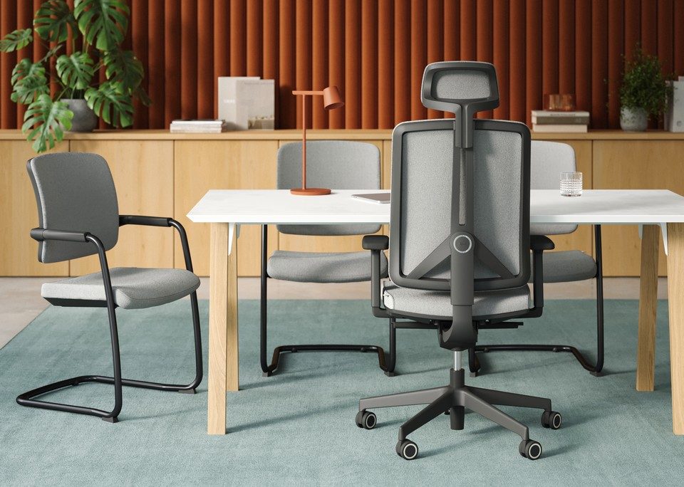 Aménagement d'un espace de réunion moderne avec un fauteuil de bureau ergonomique FLEXI gris à structure noire et têtière, associé à des chaises visiteurs luge assorties autour d'une table blanche et bois.