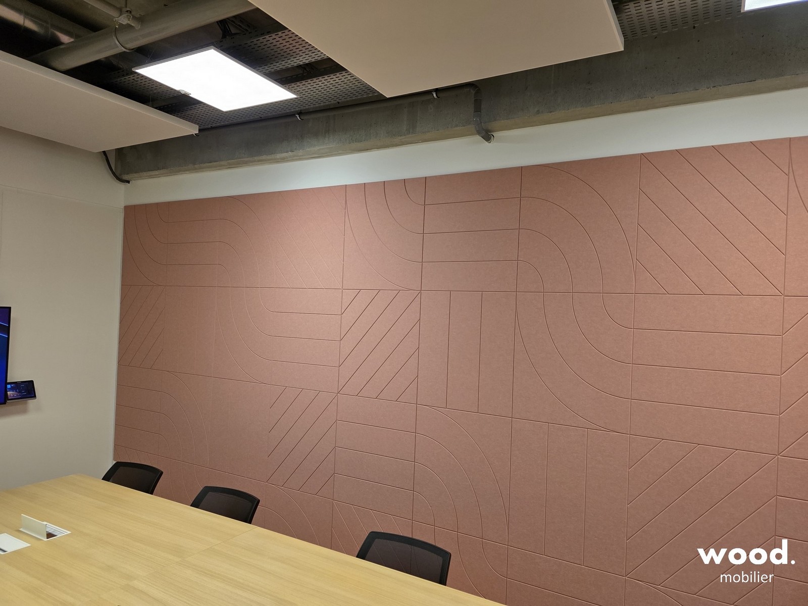 Pose de panneaux acoustiques terracotta en PET recyclé dans une salle de réunion.
