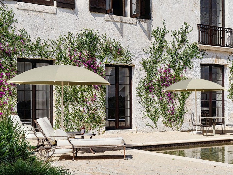 Parasol NATA coloris vert sauge intégré dans un aménagement extérieur végétalisé.