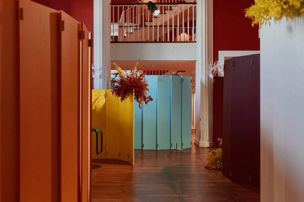 Séparateurs d'espace WOD aux couleurs vives (jaune, bleu, rouge) structurant un couloir de circulation dans un lieu de réception design.