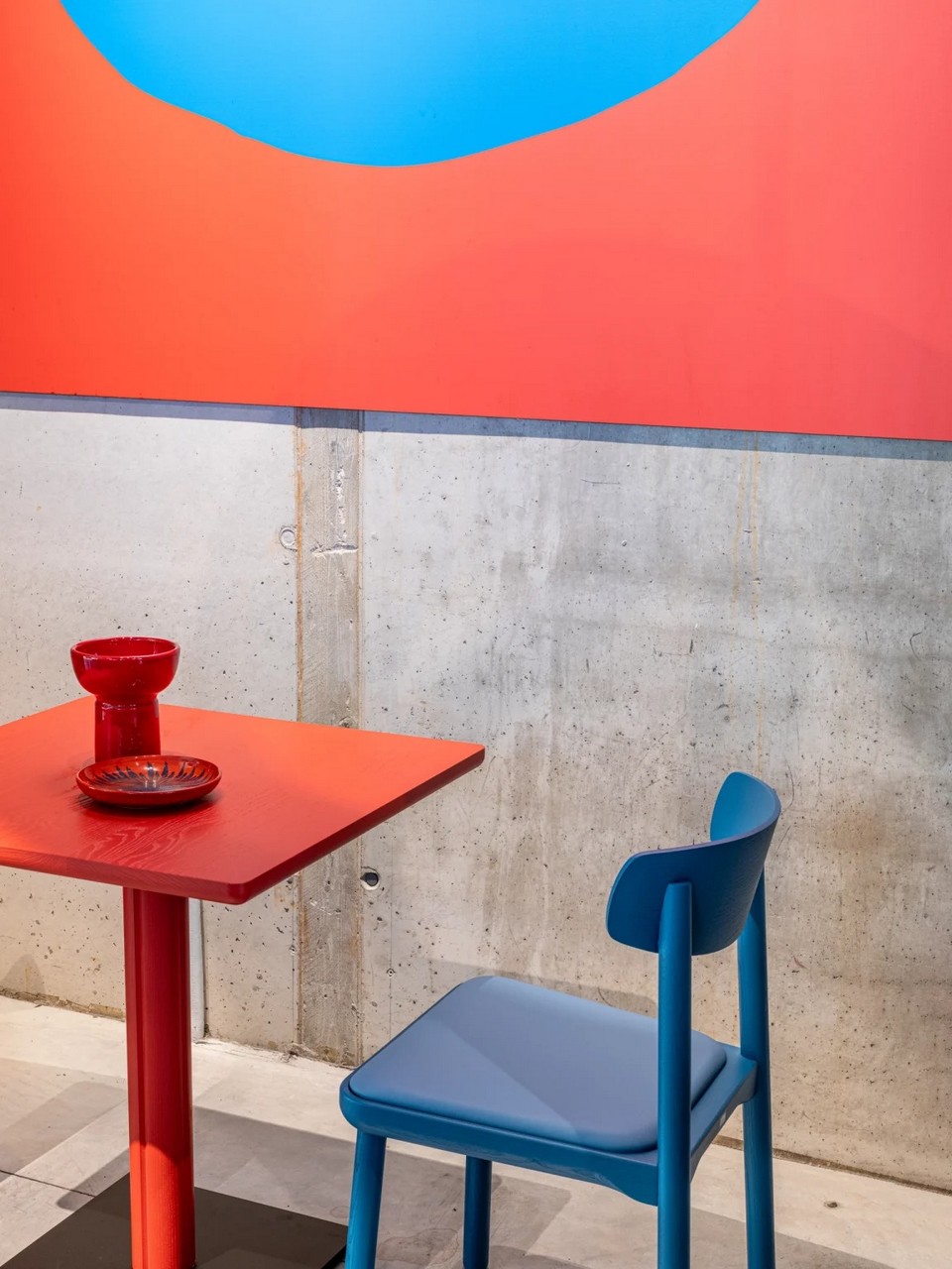 Table de bistrot ONE rouge avec plateau bois et piètement central sur base acier.