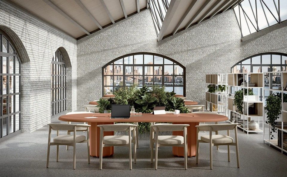 Grande table de coworking ovale SABREE terracotta avec trappes d'électrification, piètement colonne central sculptural flûté et chaises en bois LASH dans un espace collaboratif loft industriel.