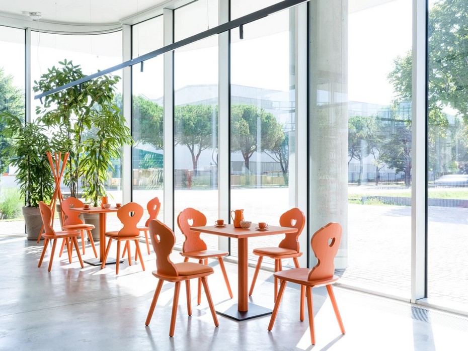 Tables de restaurant ONE orange avec chaises en bois ajourées dans une salle moderne.