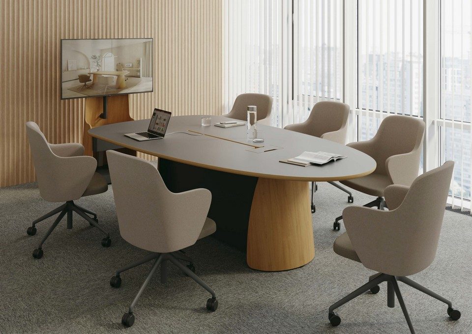 Table de réunion trapèze Dolmen avec plateau gris anthracite et piètement en bois, entourée de fauteuils beiges dans une salle de conférence moderne équipée pour la visioconférence.
