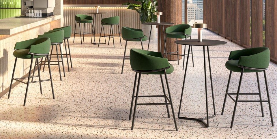 Plusieurs tabourets de bar KOALA avec assises enveloppantes vertes et piétements fins noirs disposés autour d'un comptoir et de tables hautes.